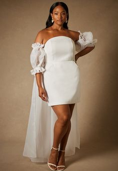 a woman in a white dress posing for the camera with her hands on her hips