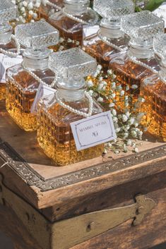 honey jars are lined up on a wooden table with flowers and labels in them for sale