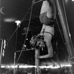 a woman is hanging upside down on a pole