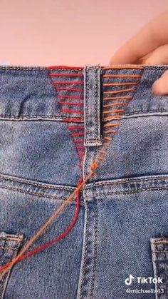 someone is holding their jeans with an orange string attached to the pocket and pulling them apart
