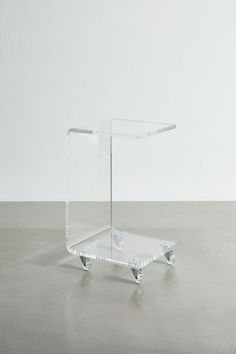 an acrylic side table with wheels on the bottom