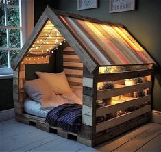 a bed made out of wooden pallets with lights in the roof and pillows on top
