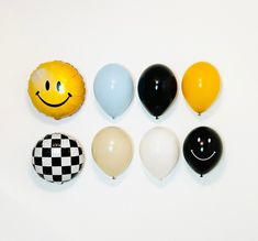 balloons with smiley faces are arranged on a white surface and one balloon has a checkerboard pattern