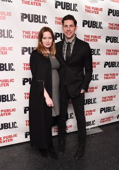 two people standing next to each other in front of a public theater sign on the red carpet