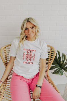 a woman sitting in a wicker chair wearing pink pants and a white t - shirt