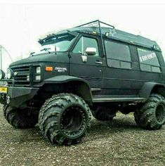 a large black truck parked on top of a gravel field