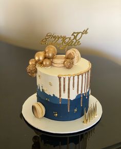 a birthday cake decorated with gold and blue icing on top of a black table