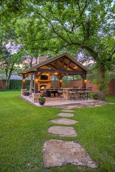 a gazebo in the middle of a yard with grass and stepping stones leading up to it