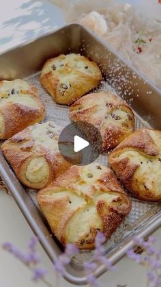 a pan filled with pastries sitting on top of a table next to purple flowers