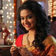 a woman in a red and gold sari holding a plate with food on it