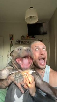 a man holding a dog with his mouth open and it's tongue hanging out