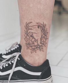 a woman's foot with a tattoo on her left leg and flowers in the middle