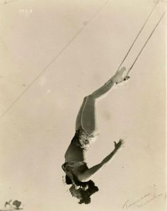 an old black and white photo of a person on a rope in the air above water