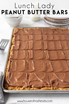 a pan filled with peanut butter bars on top of a white table next to silverware