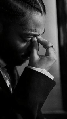 a black and white photo of a man with dreadlocks on his head holding his hand to his face