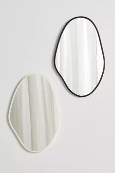 two mirrors sitting next to each other on top of a white wall with black trim