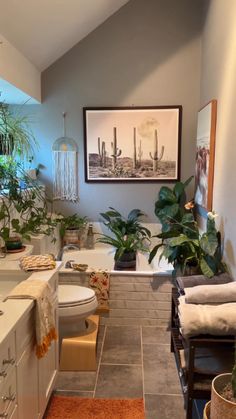 a bathroom with plants and towels on the counter next to the bathtub, toilet and sink