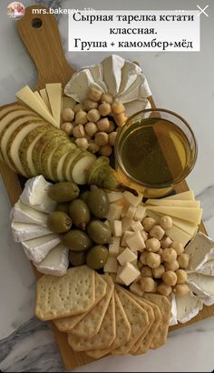 an assortment of cheeses, crackers and olives on a cutting board