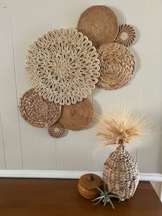 some baskets are hanging on the wall near a vase with grass in it and a pine cone