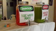 two jars filled with green and red liquid sitting on top of a white table cloth