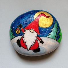 a painted rock with an image of a santa clause holding a lantern on it's head