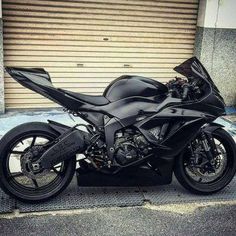 a black motorcycle parked in front of a garage door on the side of a street