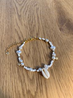 Dive into the beauty of the sea with our stunning Gold Beachy Shell Bracelet, a true treasure for those who adore the beach aesthetic. Crafted with delicate gold-toned metal, this bracelet perfectly captures the essence of a seaside escape. Each intricate shell charm reminiscent of sandy shores and ocean breeze, elegantly complemented by a lustrous pearl accent. The bracelet exudes a sense of natural beauty and coastal allure, making it a must-have accessory for beach lovers. Whether you're stro Beach Gold Jewelry, Shell Charm Bracelet, Beach Aesthetic Bracelets, Jewelry With Seashells, Shell Bracelet Aesthetic, Beach Bead Bracelet, Things To Put On A Bracelet Words, Sea Shell Jewelry Aesthetic, Ocean Jewelry Aesthetic