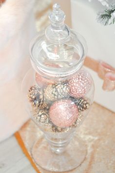 a glass jar filled with christmas ornaments on top of a table