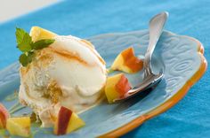 an ice cream sundae on a blue plate with a silver fork and spoon next to it