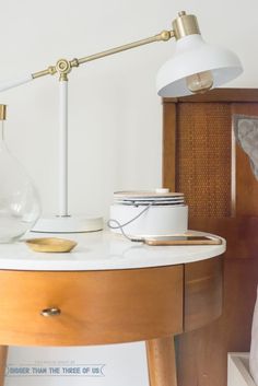 a table with a lamp on it next to a bed and other items in the room