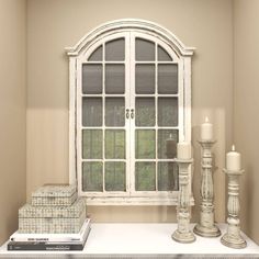 a white window sitting on top of a shelf next to a candle and some books