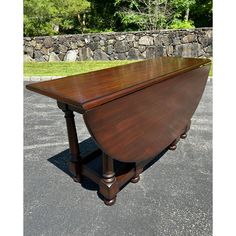 a large wooden table sitting on top of a parking lot next to a stone wall