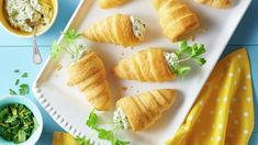 several croissants on a white plate with green garnish and dip