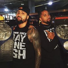 two men standing next to each other holding up wrestling belts