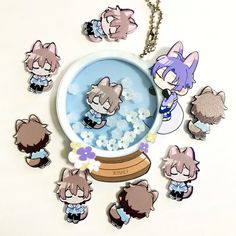 an assortment of keychains with cartoon characters on them sitting in front of a snow globe