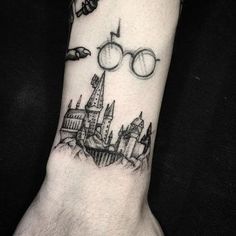 a person's wrist with a harry potter tattoo on it and hogwarts flying over the castle
