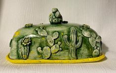 a green ceramic covered with cacti and birds on it's back end