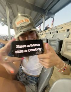 a woman holding up a cell phone in front of her face at a baseball game