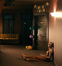 a woman sitting on the floor in front of a doorway with balloons and streamers