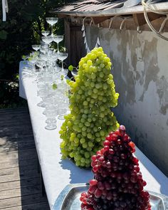 some grapes are sitting on a table with wine glasses in front of them and one is shaped like a christmas tree