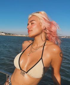 a woman with pink hair standing on a boat