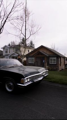 an old black car parked in front of a house