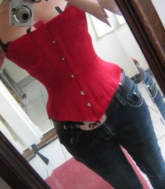 a woman taking a selfie in front of a mirror wearing jeans and a red top