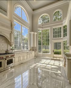 a large kitchen with marble flooring and white walls, windows overlooking the trees outside