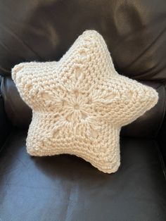 a crocheted star pillow sitting on top of a leather chair