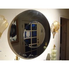 a round mirror hanging on the wall above a sink in a room with balloons and other decorations