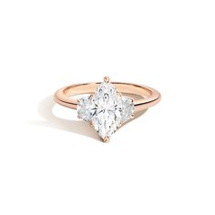 a rose gold engagement ring with two pear shaped diamonds on the band and an oval diamond in the center