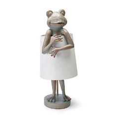 a frog lamp with a white shade on it's head and arms folded up