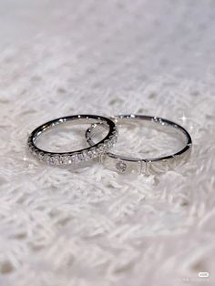 two wedding rings sitting on top of a white furnishe covered floor next to each other