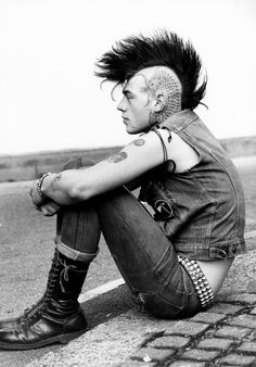 a person sitting on the ground with their arms crossed and his head shaved in mohawks